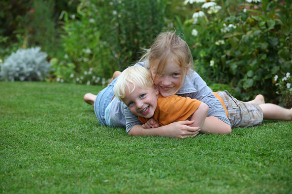Kinder toben auf Rasenfläche